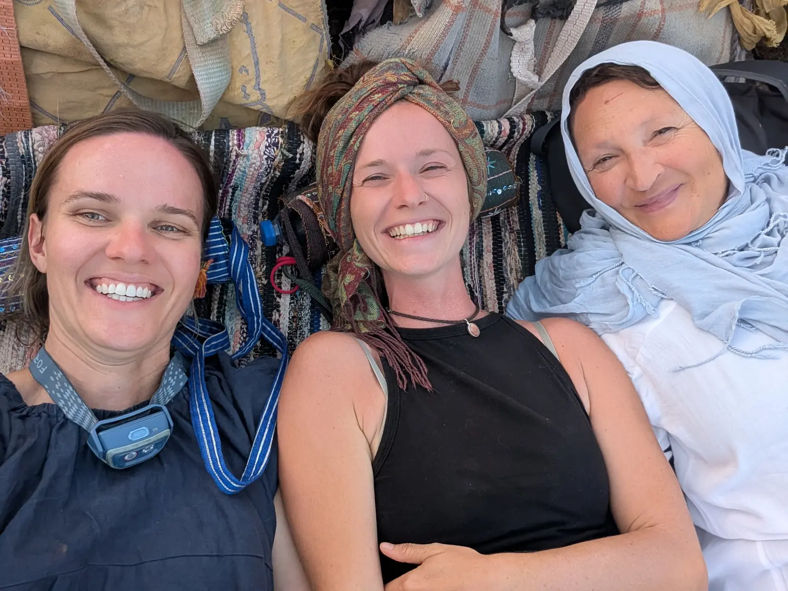 Drei Frauen lachen gemeinsam mit einem Kamel in der Wüste des Süd-Sinai