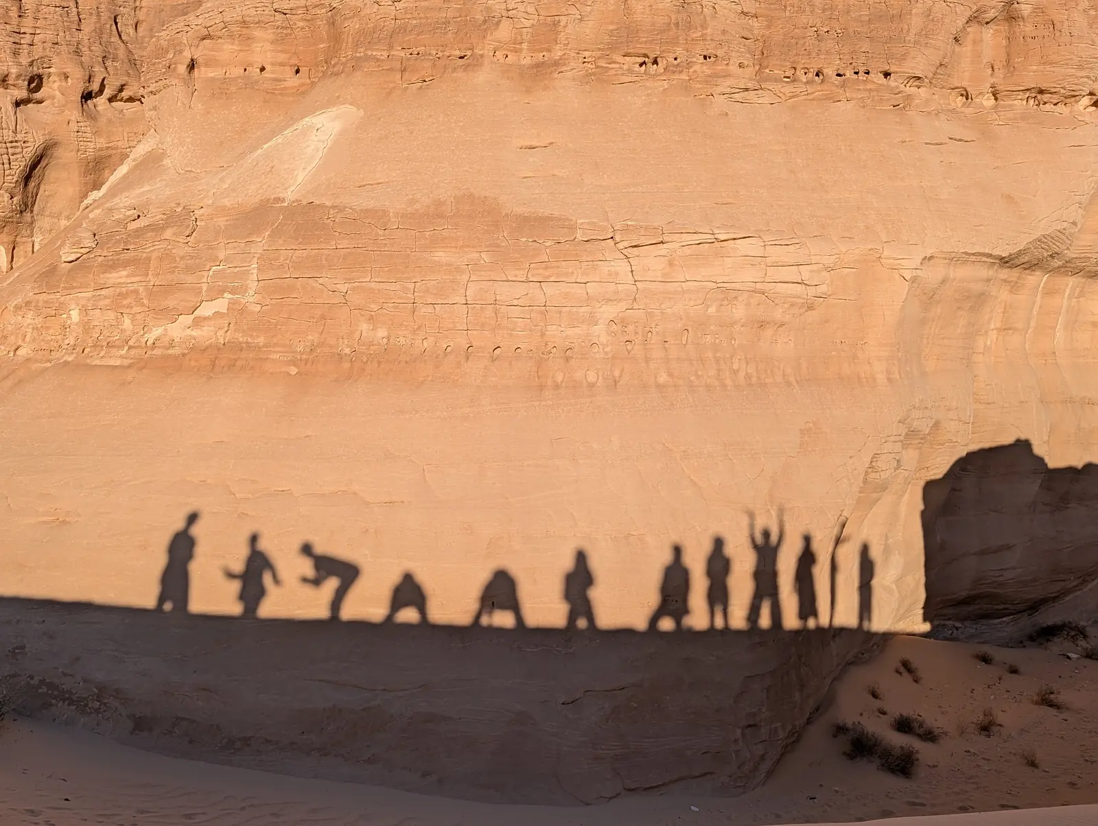 Schatten der Reisegruppe an goldener Sandsteinwand in der Wüste Sinai