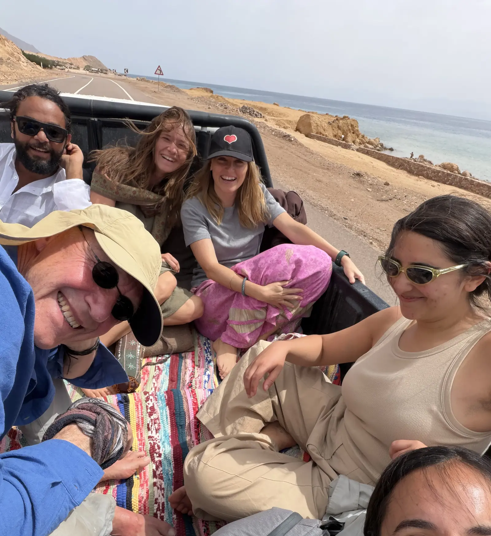Lachende Reisegruppe fährt auf der Ladefläche eines Jeeps entlang der Küste des Roten Meeres im Sinai