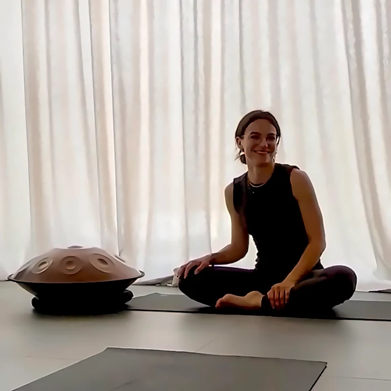 Melanie Wegerer sitzt im Schneidersitz neben einer Handpan im Yogaraum
