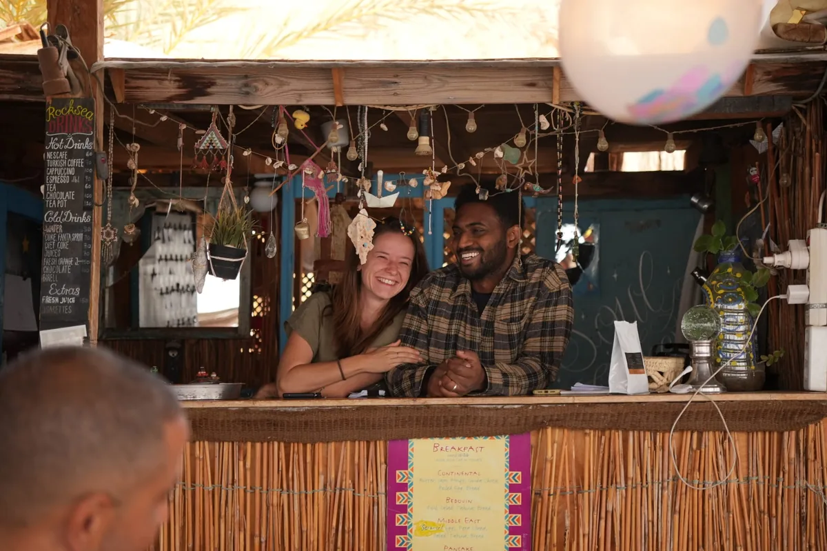 Elena Steinmann und ihr Mann lachen hinter der Bar des RockSea Camps